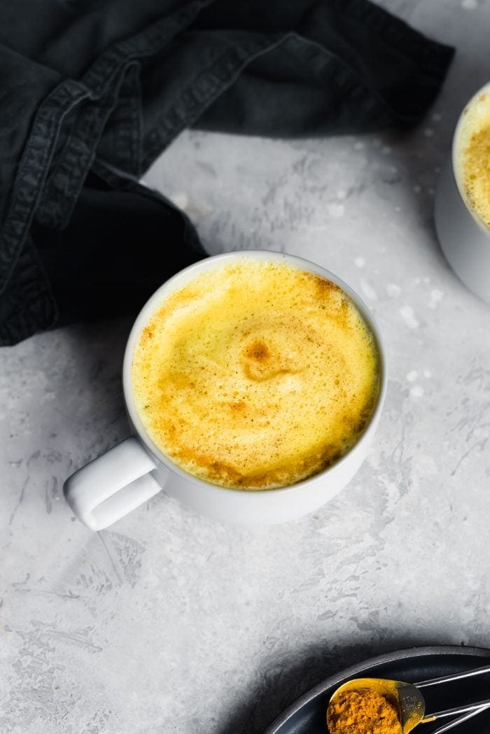 Overhead view of a mug of frothy golden milk.