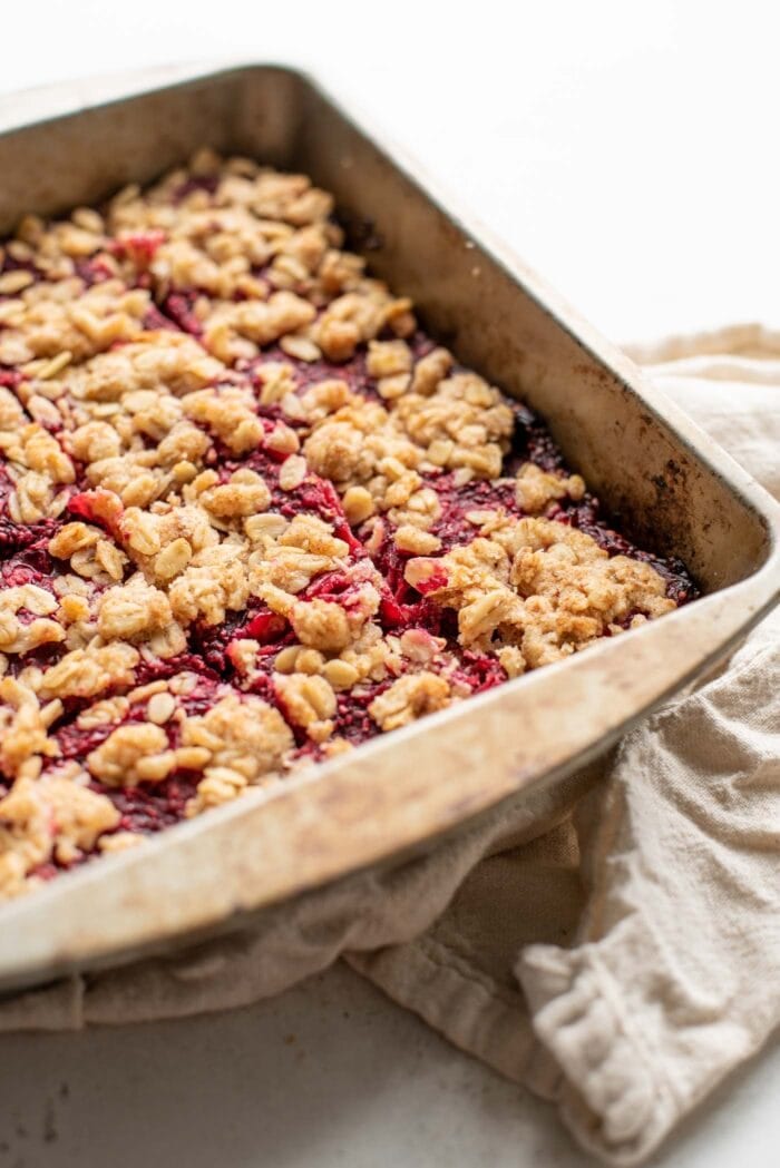 Cranberry oatmeal bars sliced into 16 squares in a square baking pan.