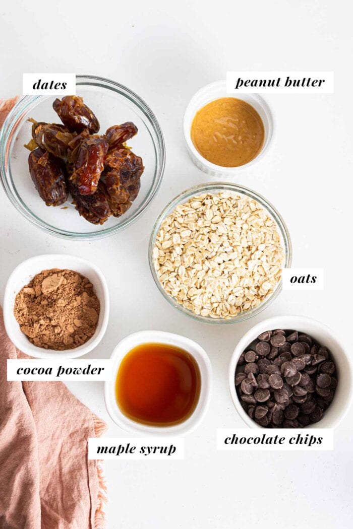 Dates, peanut butter, chocolate and oats in bowls on a counter.