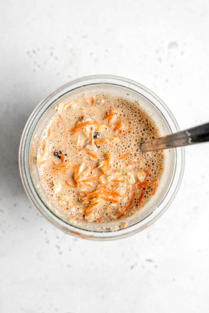Oats, carrots and almond milk in a glass jar with a spoon.
