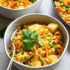 Vegan Pineapple Cashew Cauliflower Rice in a skillet with a wooden spoon.