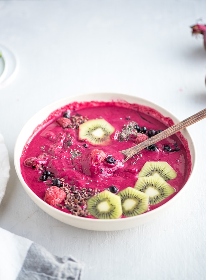 A pink smoothie bowl topped with kiwi and chia seeds.