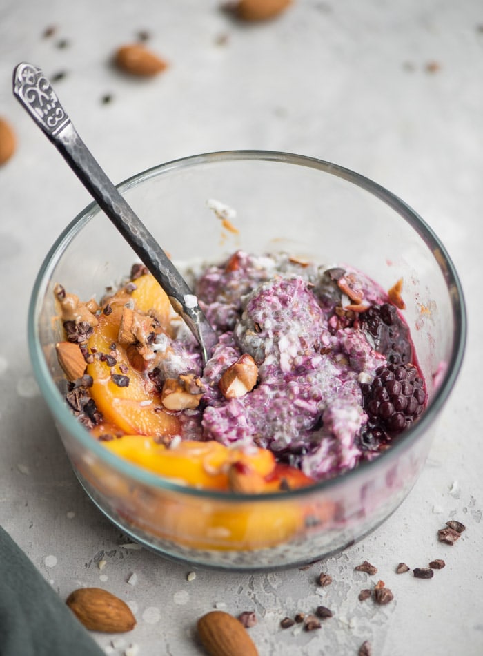 Chia and coconut pudding in a bowl with peaches and berries.