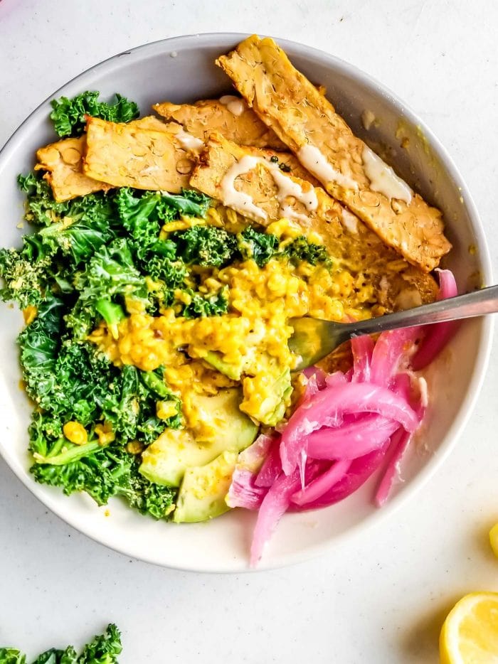 A bowl of savory oatmeal with pickled onion, tempeh and kale.