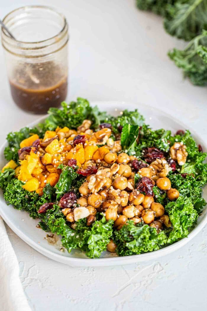 A kale salad topped with squash, chickpeas, cranberries, hemp seeds and walnuts.