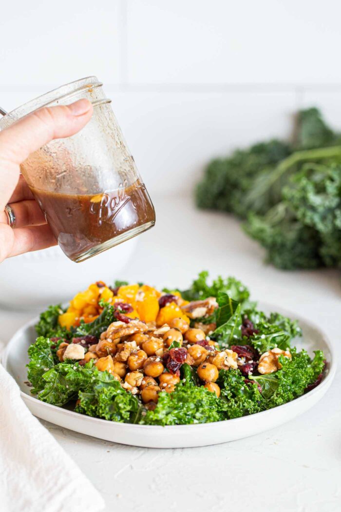 A kale salad topped with squash, chickpeas, cranberries and walnuts.