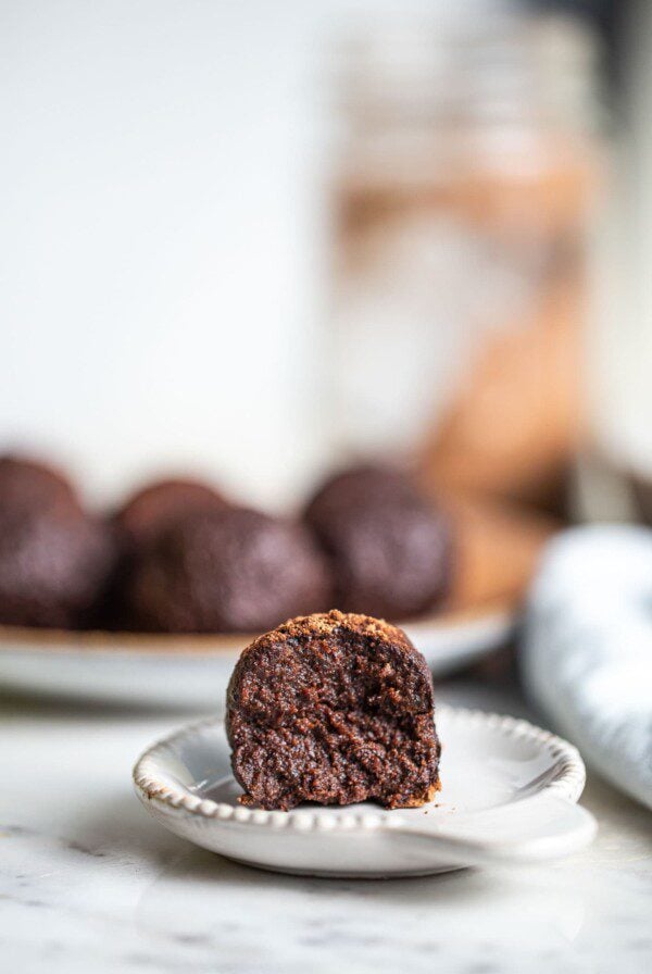 A tahini chocolate date ball with a bite taking out of it sitting on a small plate.