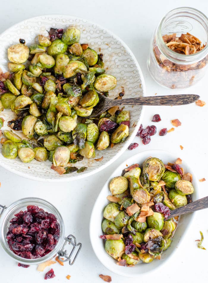 Two bowls of roasted brussels sprouts with cranberries and coconut bacon.