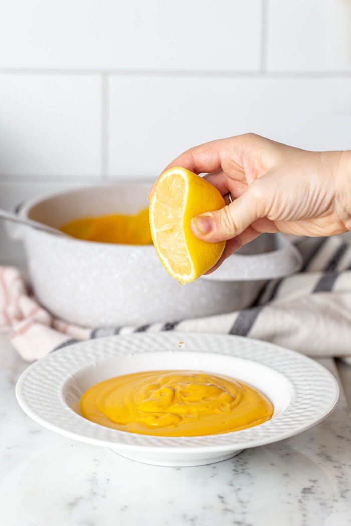 Squeezing lemon into a bowl of soup.