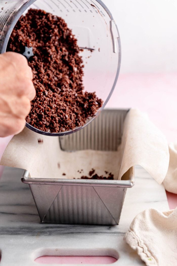 Dumping chocolate dough from a food processor into a loaf pan.