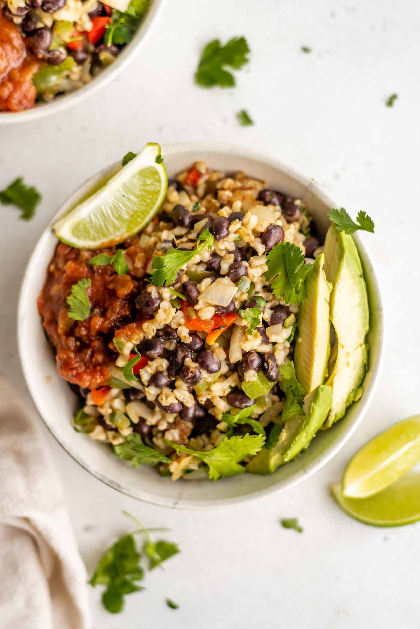 A bowl of rice and beans topped with avocado and salsa.