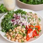 A big bowl filled with chickpeas, farro, kale, roasted red peppers and red onion.