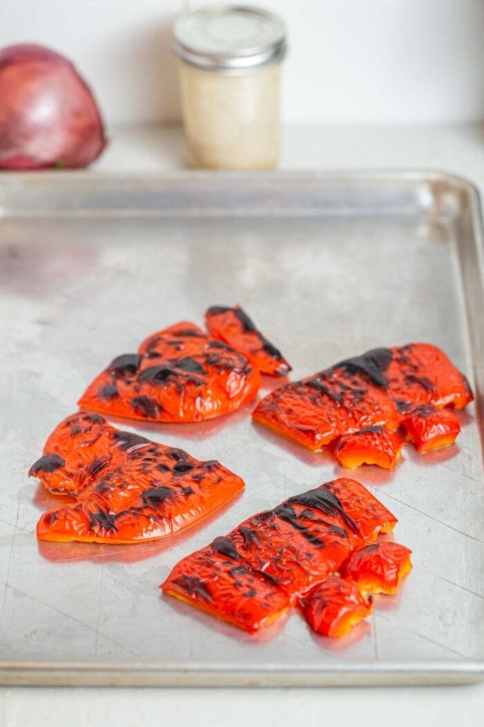 Roasted red peppers on a baking tray.