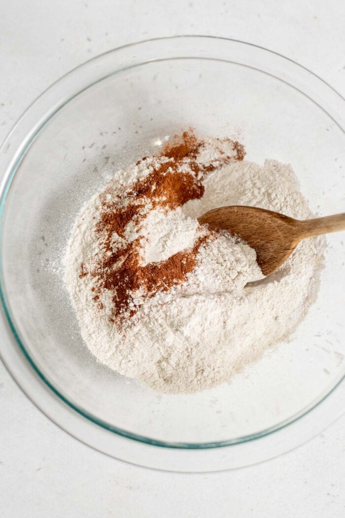 Flour, cinnamon, baking powder and salt in a mixing bowl with a spoon.