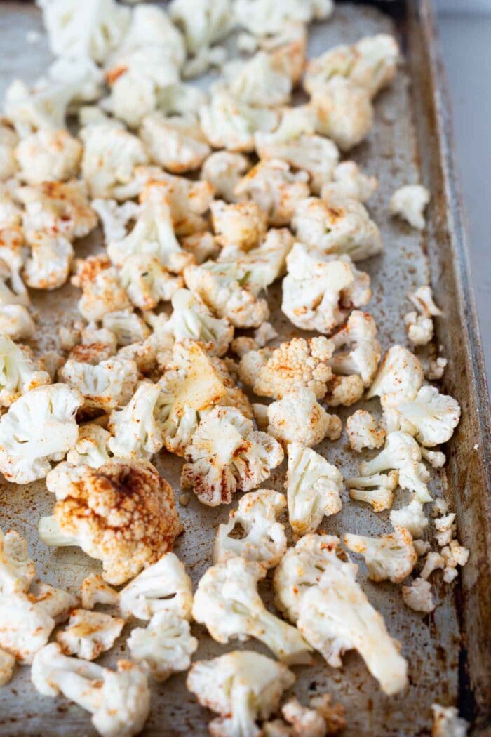 Chopped cauliflower on a parchment paper lined baking tray.