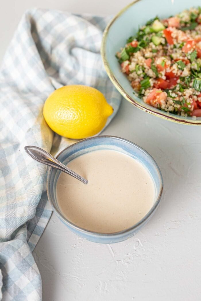 Creamy tahini sauce in a small dish with a spoon.