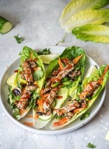 Three tofu lettuce wraps with grated carrot on a plate.