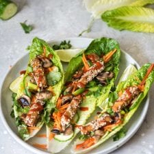 Three tofu lettuce wraps with grated carrot on a plate.