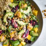 A plate of quinoa avocado salad with beets, squash and mustard dressing.