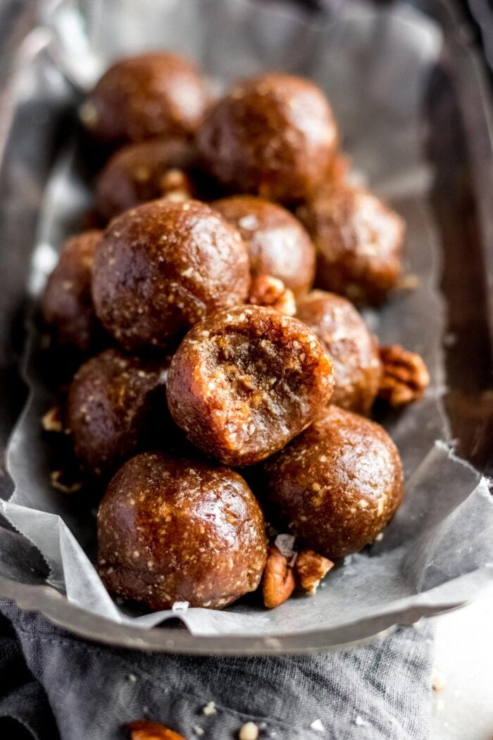 A plate of pecan energy balls. One on top has a bite out of it.