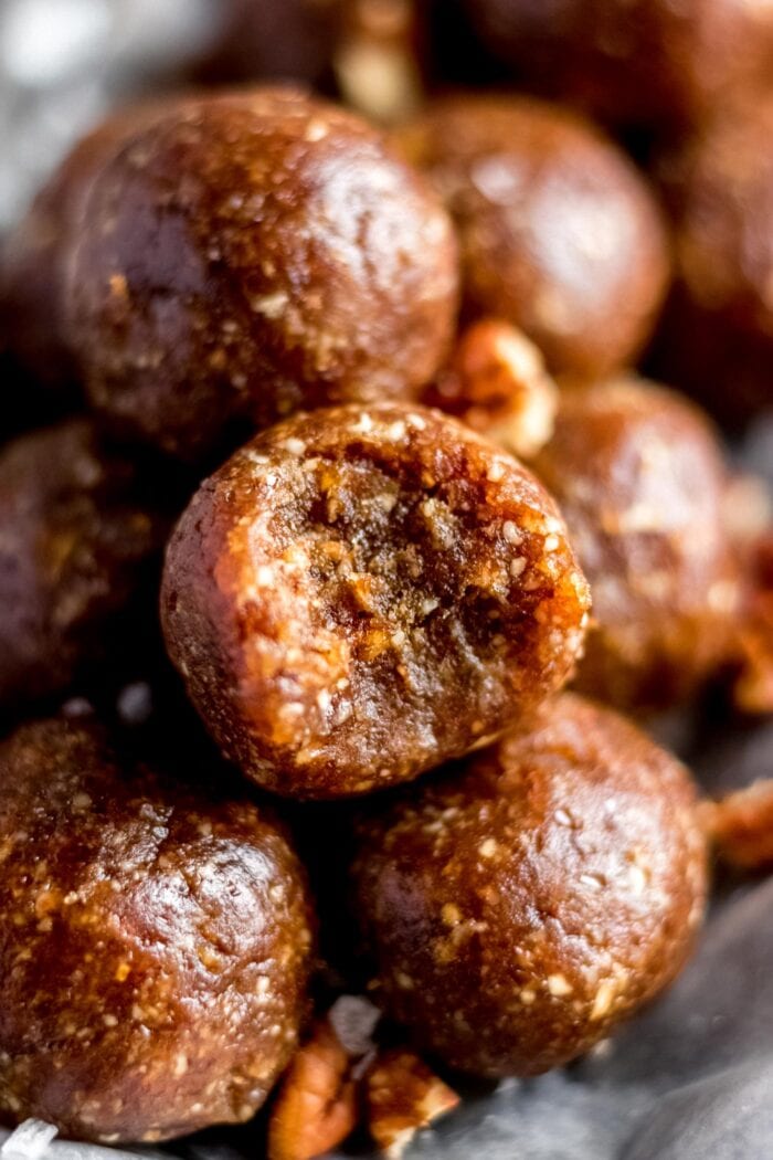 Close up of a plate of pecan energy balls. One on top has a bite out of it.