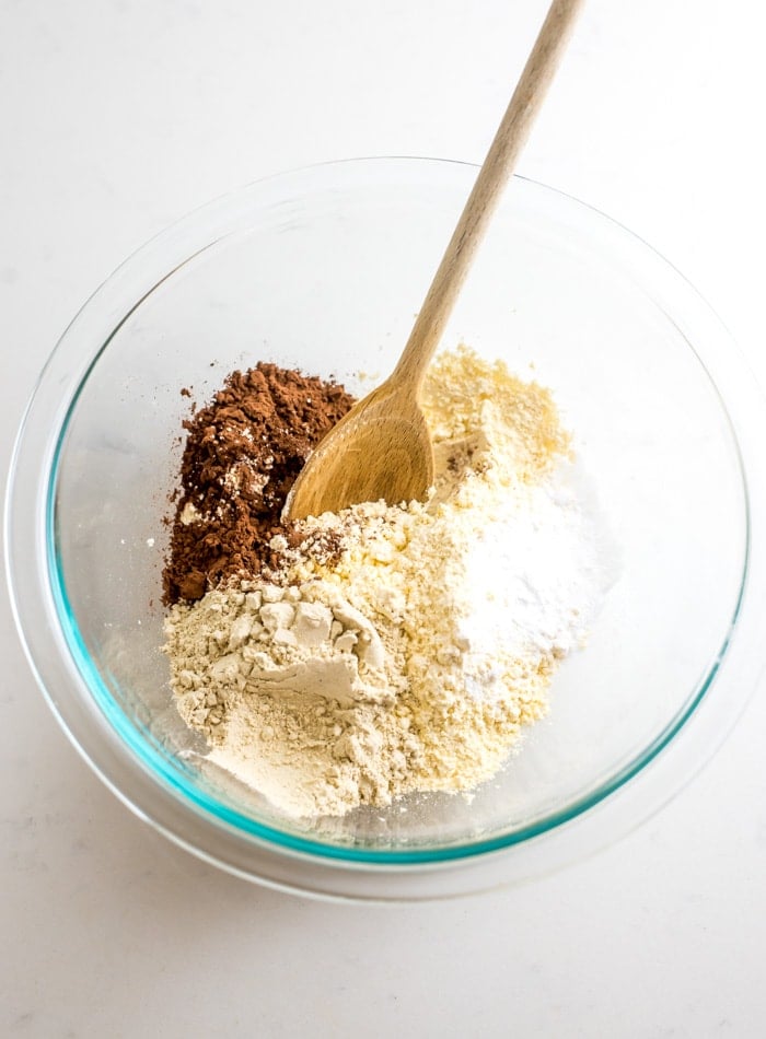 Chickpea flour, cocoa powder and baking powder in a glass mixing bowl.