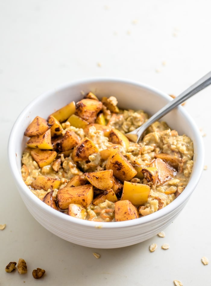 A bowl of oatmeal topped with bits of stewed apples.