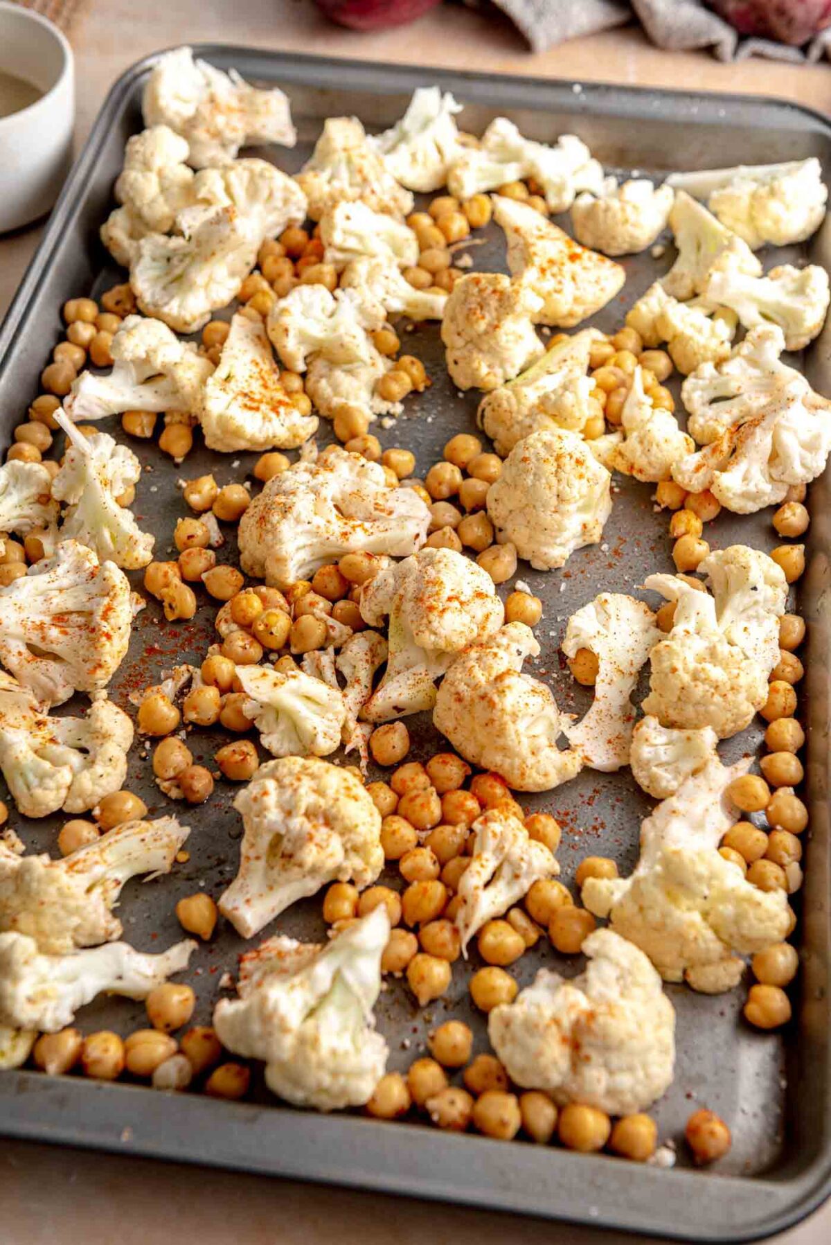 Chopped cauliflower and chickpeas on a baking tray.