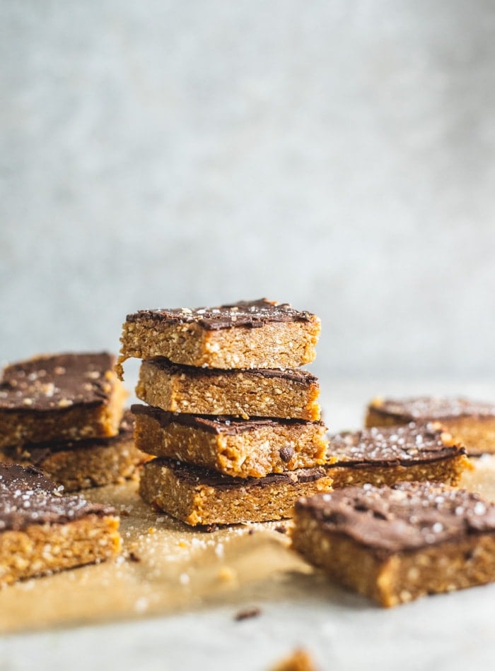 Stack of 4 dessert bars made with cashews topped with a thin layer of chocolate.