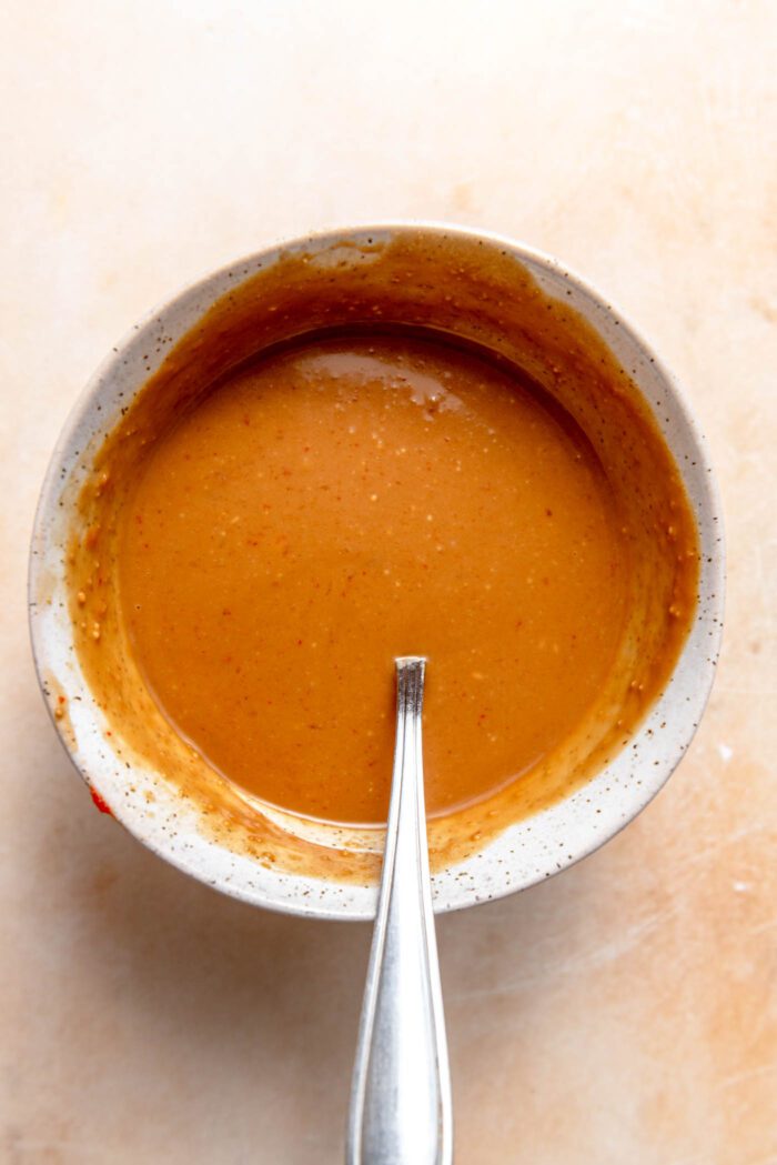Peanut sauce in a small bowl with a spoon in it.