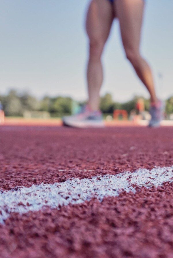 Woman running on a track performing a conditioning workout.