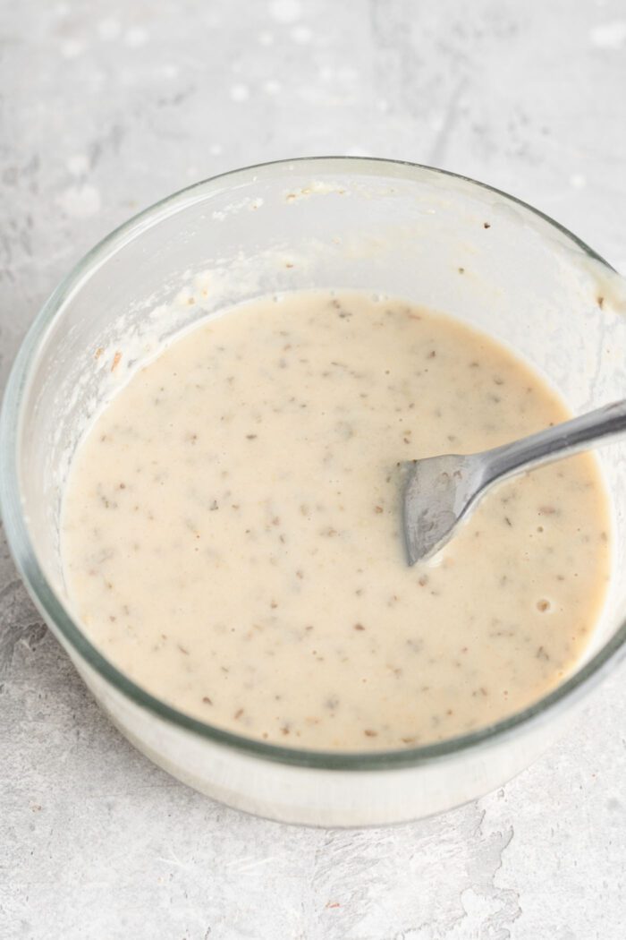 Tahini ranch dressing mixed up in a small glass bowl with a fork resting in it.