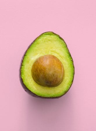 Ripe cut avocado on a pink background.