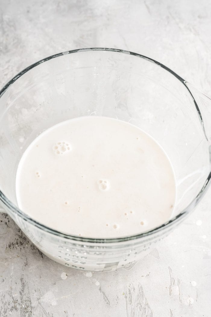 Creamy, healthy homemade oat milk in a glass measuring cup.