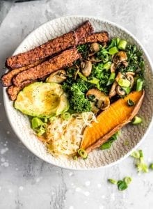 Overhead shot of a vegan tempeh bacon, avocado, kale and mushroom sweet potato breakfast bowl.