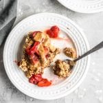 A square of baked apple cinnamon oatmeal topped with strawberries on a plate.