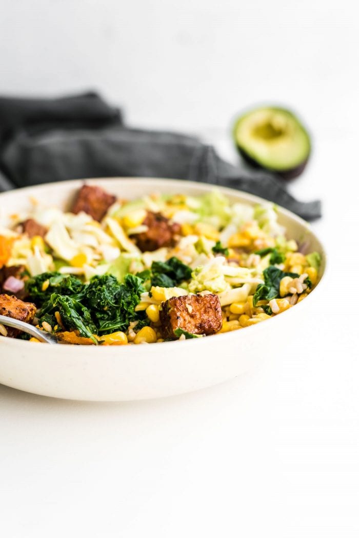 BBQ tempeh and kale in a bowl with coleslaw and avocado.