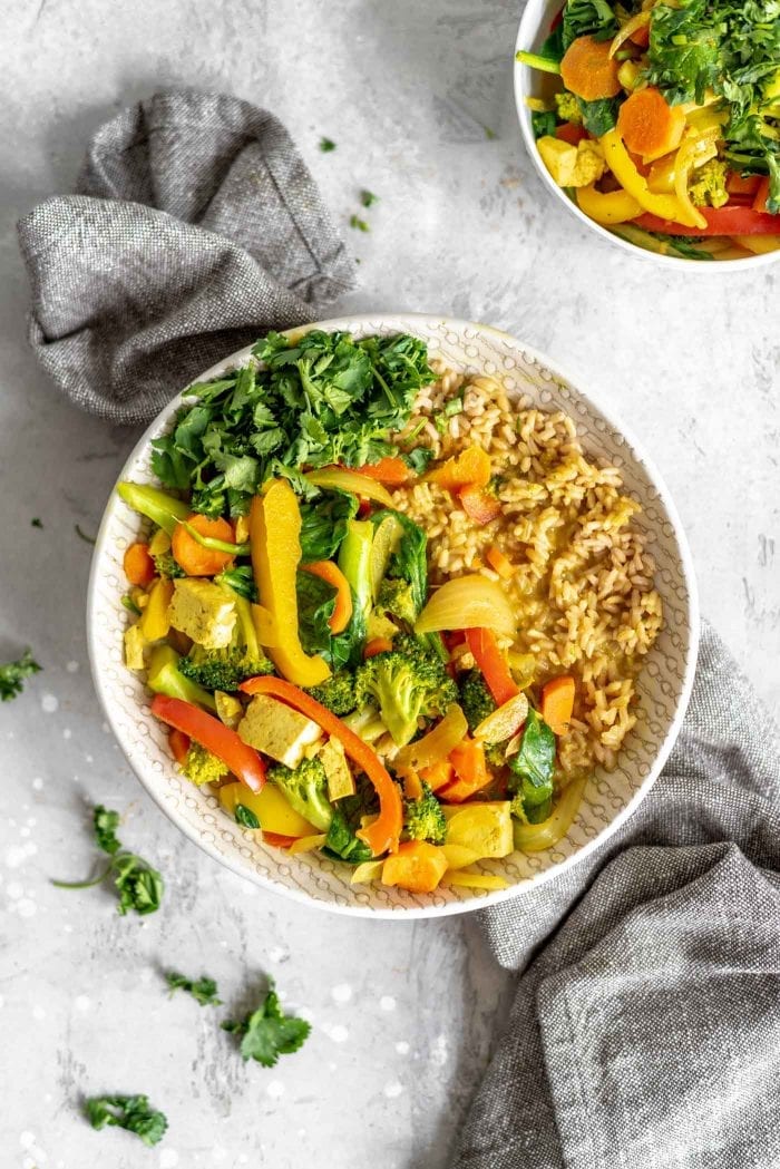 Quick and easy coconut veggie curry in a bowl with cilantro, tofu and rice.