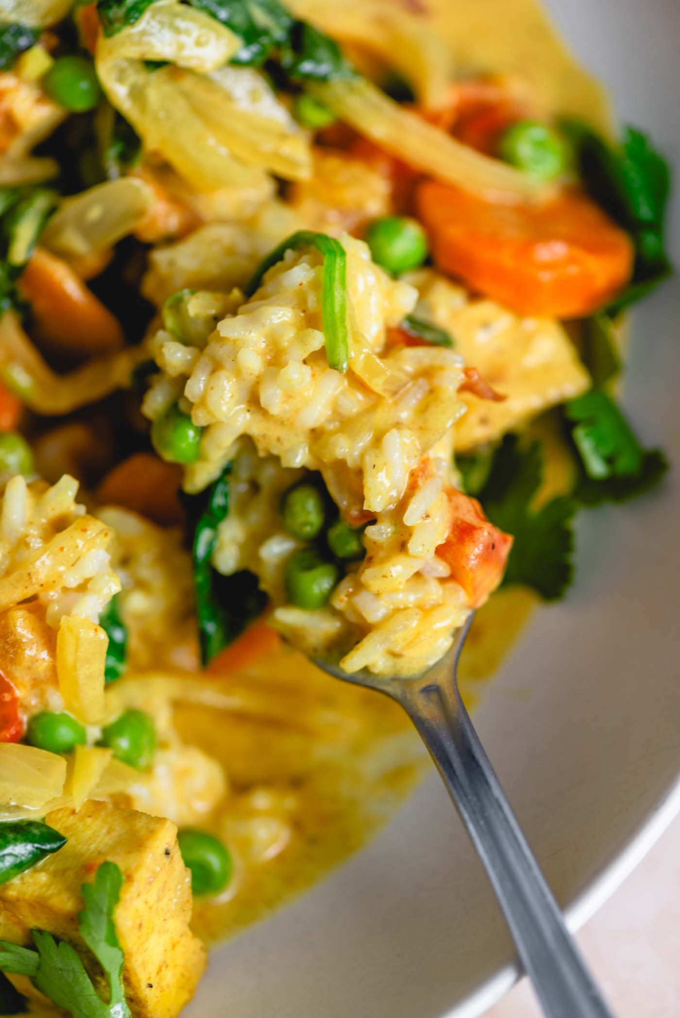 A forkful of vegetarian curry with vegetables and rice, highlighting the rich texture and vibrant ingredients.