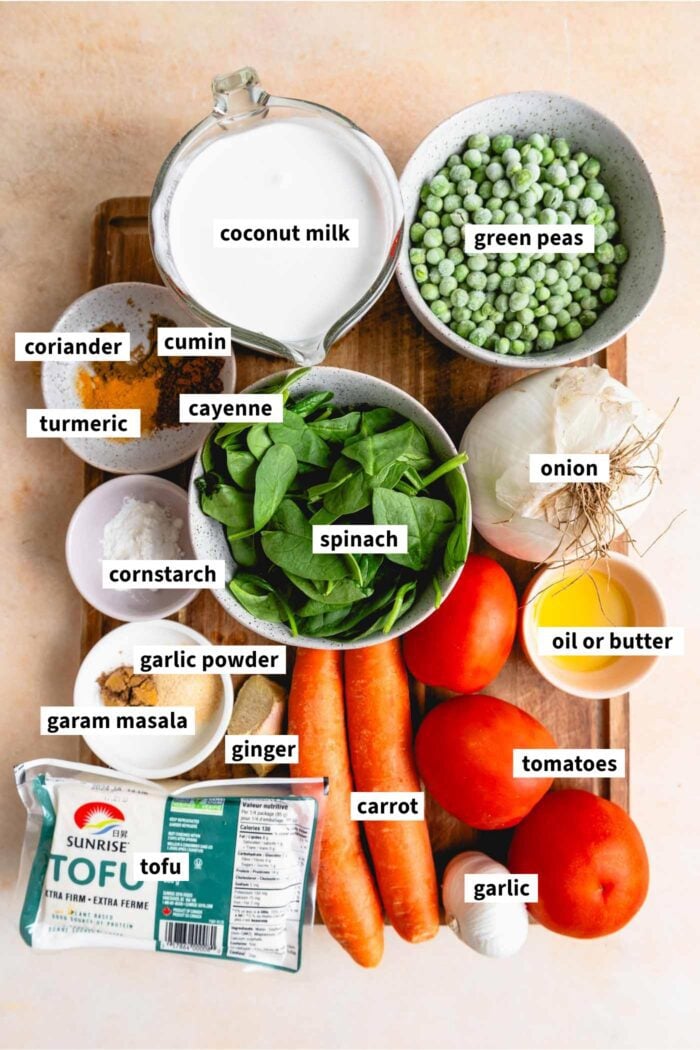 Ingredients for a vegan curry recipe with carrot, tomato, coconut milk, tomatoes, green peas and tofu.
