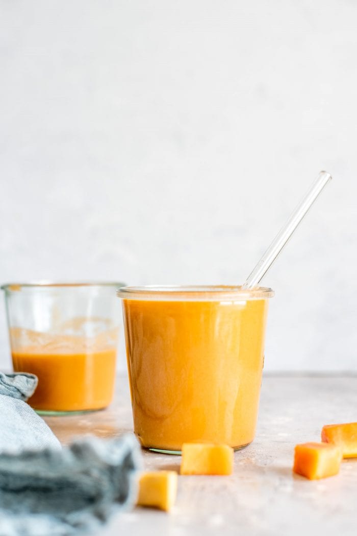 Two glasses filled with creamy vegan papaya smoothies.