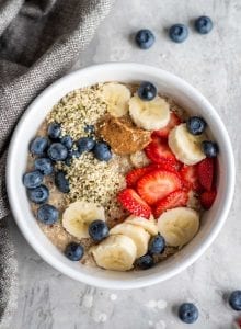 5-minute breakfast quinoa in a white bowl topped with berries, banana, hemp seeds and almond butter.