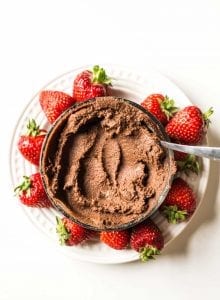 Chocolate hummus dip with fresh strawberries on a white plate.