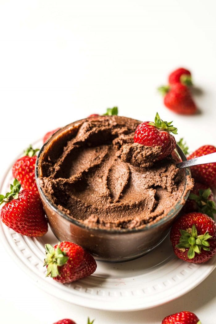 A fresh strawberry being dipped into chocolate hummus.