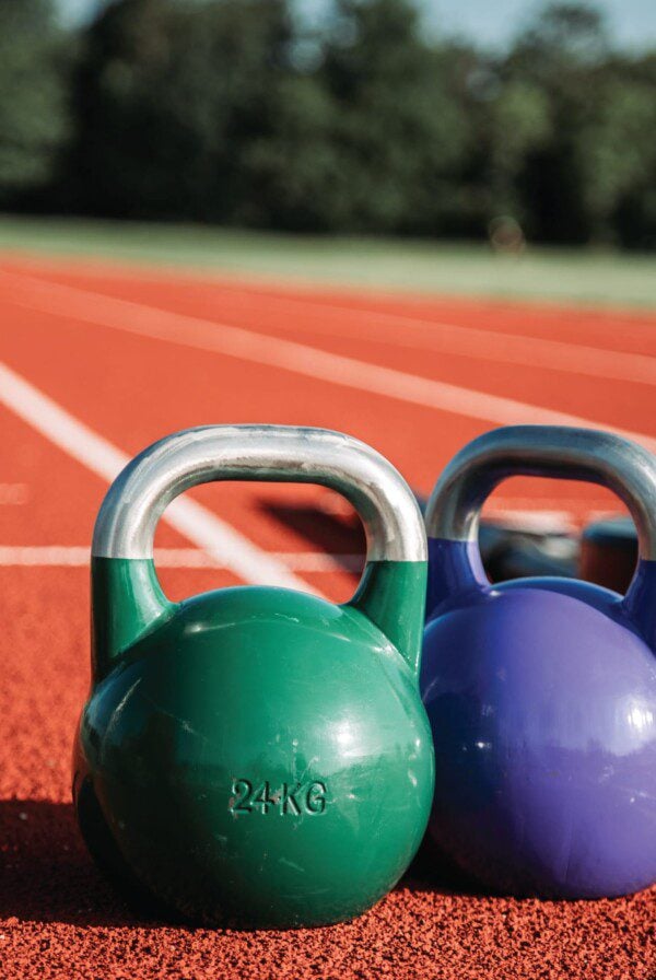 Two kettlebells sitting on a running track.