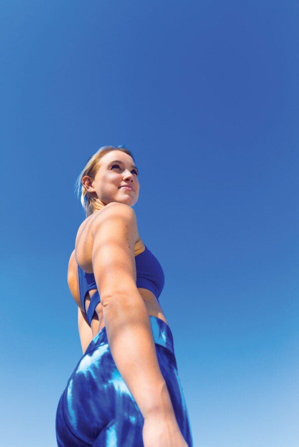 Fit woman in blue workout gear looking back over her shoulder.