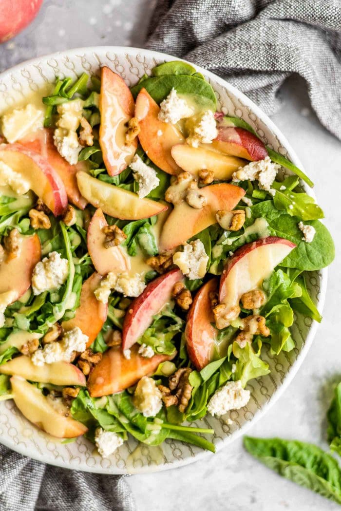 Close up shot of a green salad with fresh peach.