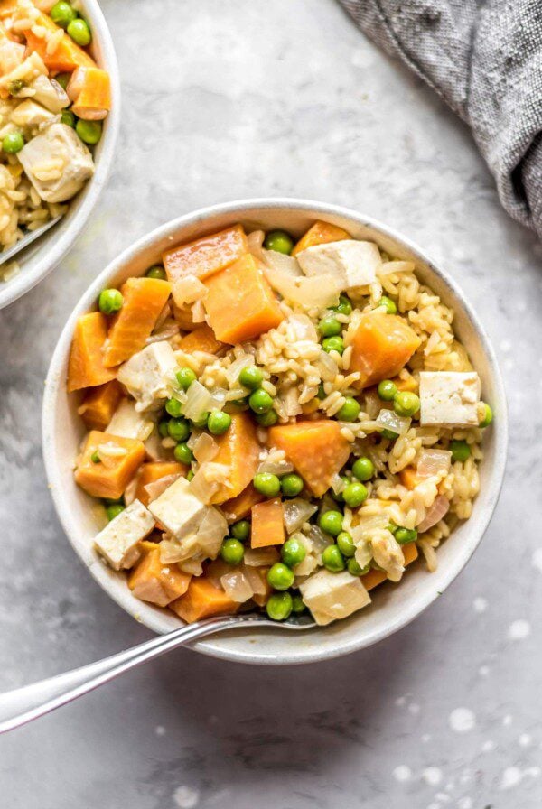 Small bowl of sweet potato pea curry with tofu and brown rice.