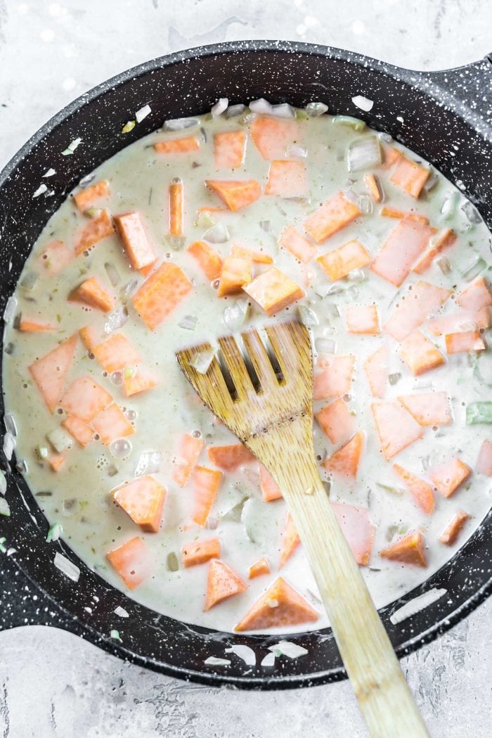 Coconut milk in a pan with sweet potato, onion, garlic and ginger.