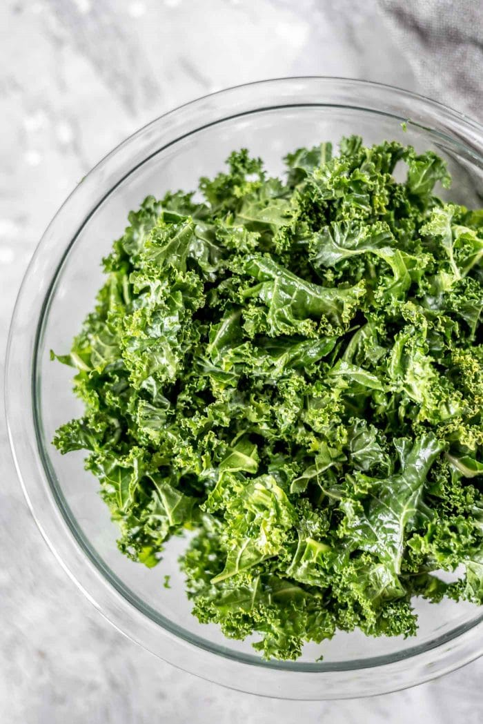 Massaged, chopped kale in a large glass mixing bowl.